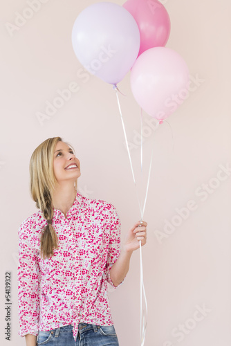 Woman Looking Up At Balloons Against Pink Background