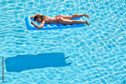 Young woman in red swimsuit bakes lying on inflatable mattress