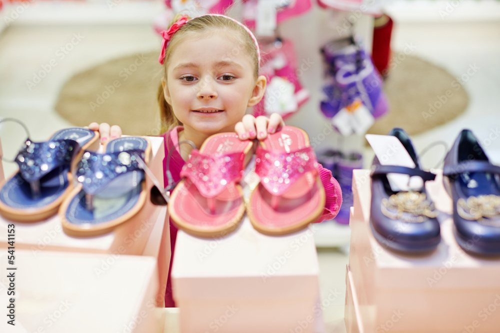 Little girl looks up on toeless shoes that stands on top of shoe Little girl looks up on toeless shoes that stands on top of shoe