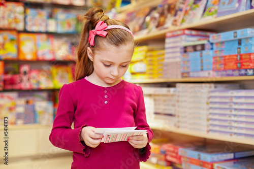 Little girl views envelopes in book department of store