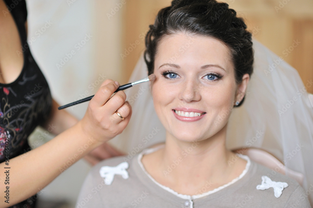 Young beautiful bride applying wedding make-up by make-up artist Young beautiful bride applying wedding make-up by make-up artist