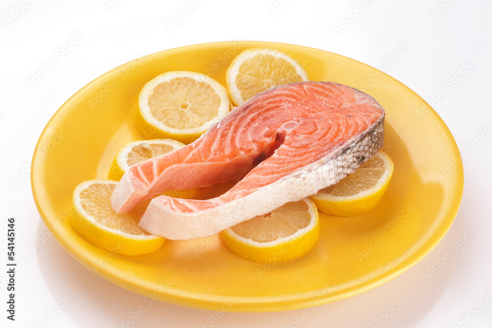 filet of raw salmon on lemons in yellow plate.