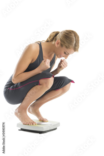 Fototapeta Naklejka Na Ścianę i Meble -  Excited Woman Weighing Herself On Weight Scale