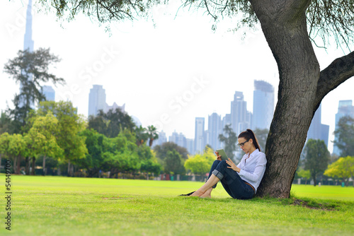 Beautiful young woman with  tablet in park