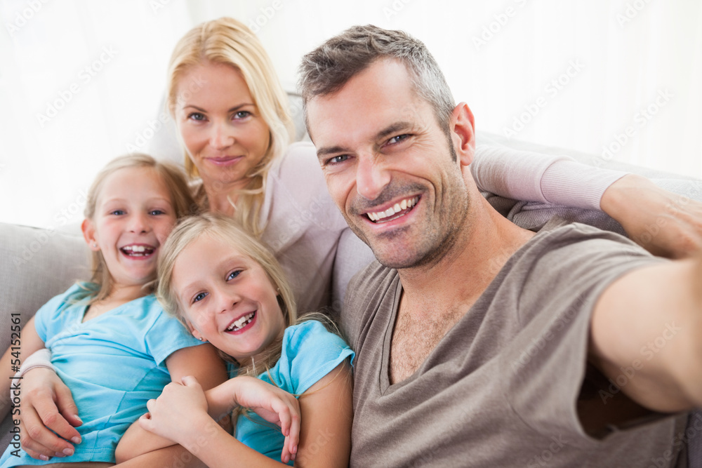 Man taking picture of wife and twins sitting on a couch Man taking picture of wife and twins sitting on a couch