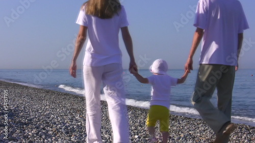 Young parents with the small child walk on the seaside