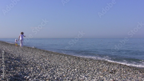 Young woman with the child walk on seaside