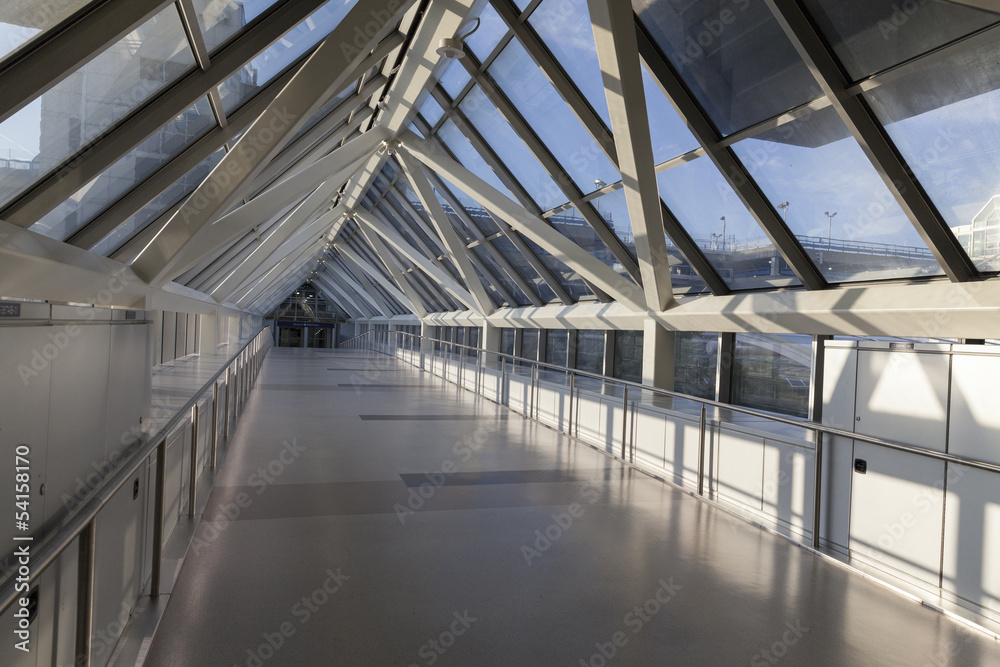 An empty pedestrian bridge at an airport is light by early morni