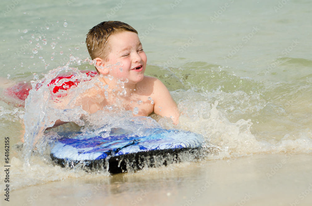 Child surfing on bodyboard at beach