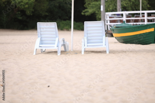 white pool chairs on sand beach