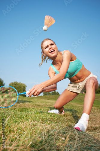 Fitness, young woman playing badminton in a city park