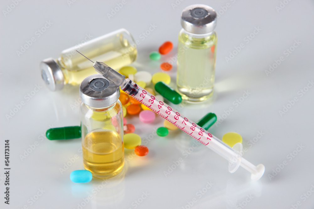 Medical bottles syringe and tablets on light gray background