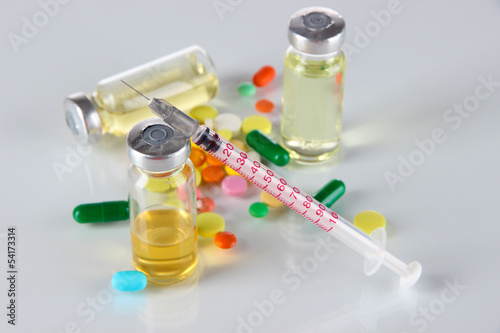 Medical bottles syringe and tablets on light gray background