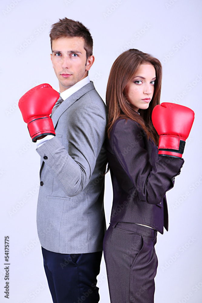 Young business people in boxing gloves on grey background Young business people in boxing gloves on grey background