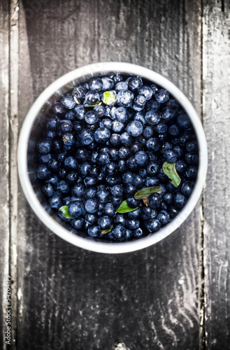 Blueberries in a bowl with leaves on wooden old rustic  backgrou