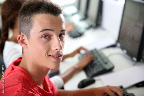 High-shool boy sitting in front of desktop computer