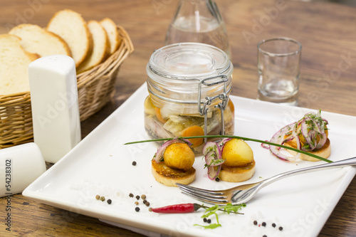 pickled herring in a glass jar with potato canapes photo