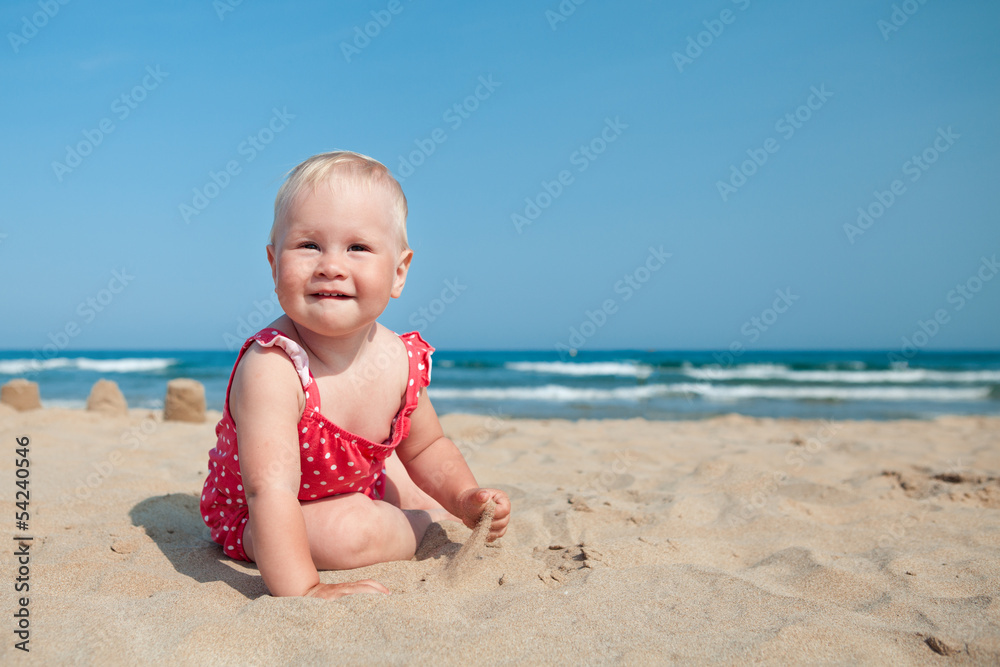Little girl sitting on sand at beach Little girl sitting on sand at beach