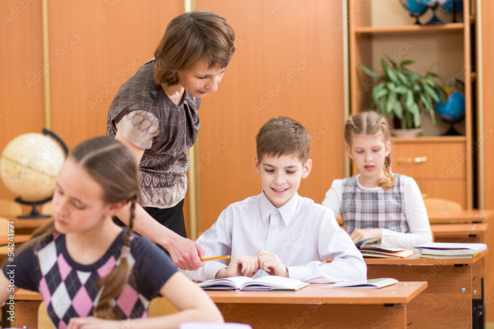 Schoolkids work at lesson. Teacher controling learning process. Schoolkids work at lesson. Teacher controling learning process.
