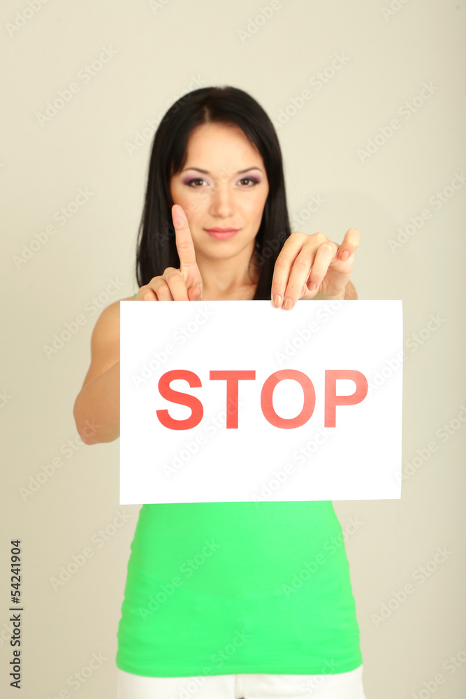 Girl showing stop sign on grey background Girl showing stop sign on grey background