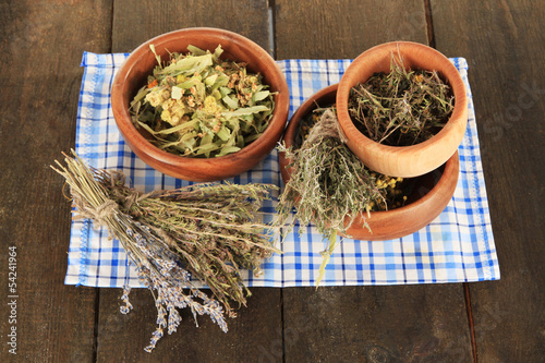 Medicinal Herbs in wooden bowls on napkin on wooden table