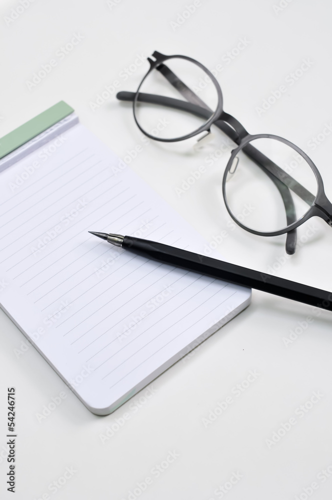 Eye glasses, blank notepad, and mechanical pencil on the table Eye glasses, blank notepad, and mechanical pencil on the table