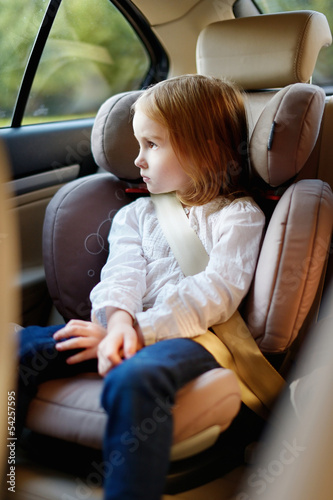 Adorable little girl sitting in car seat