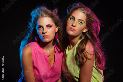 Two sexy retro 80s fashion girls with long blonde hair. Twin sis