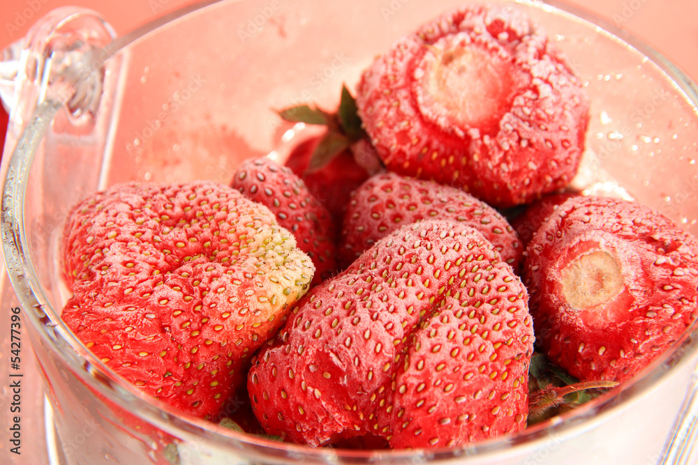 Frozen strawberries in bucket of ice on red background Frozen strawberries in bucket of ice on red background
