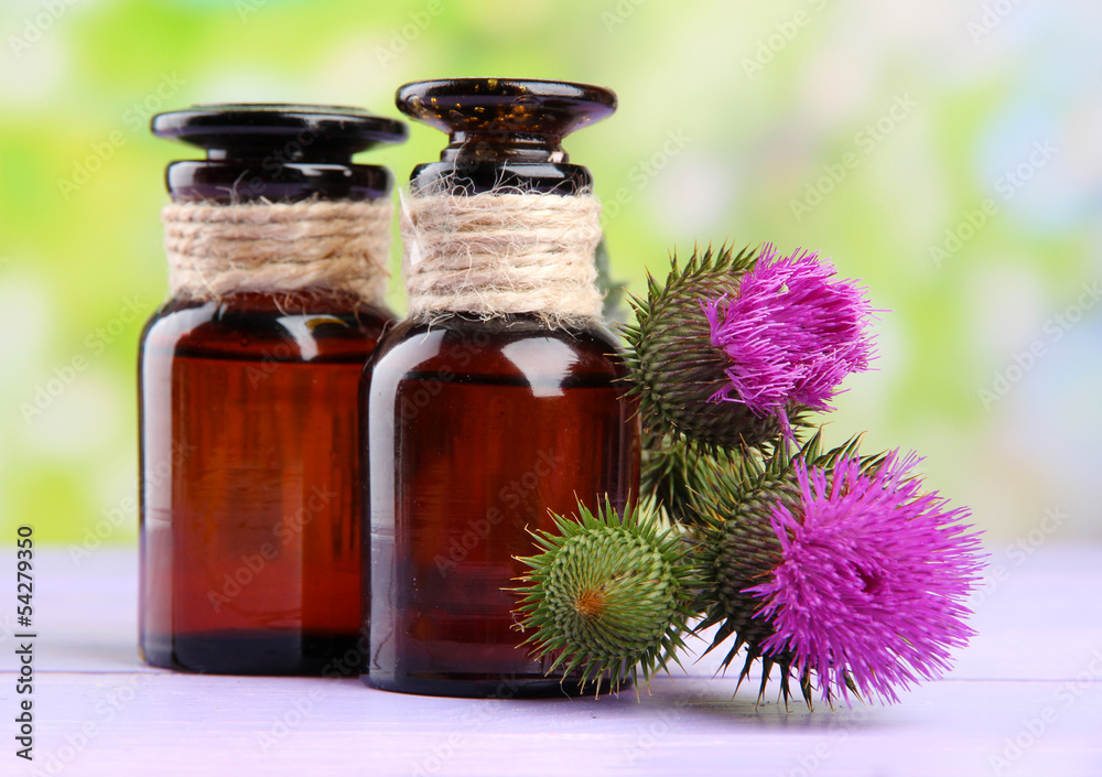 Medicine bottles with thistle flowers on nature background Medicine bottles with thistle flowers on nature background