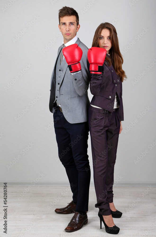 Fototapeta premium Young business people in boxing gloves on grey background