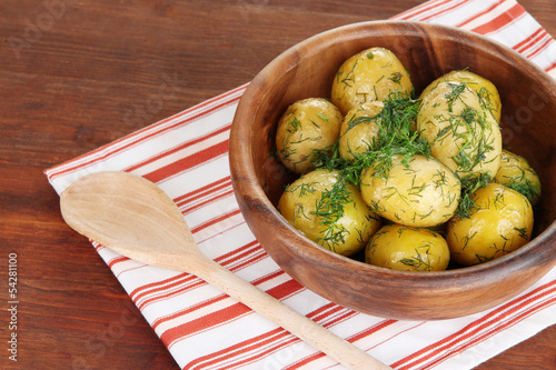 Boiled potatoes on wooden bowl on napkin on wooden table