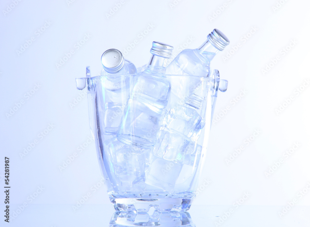 Minibar bottles in bucket with ice cubes, isolated on white