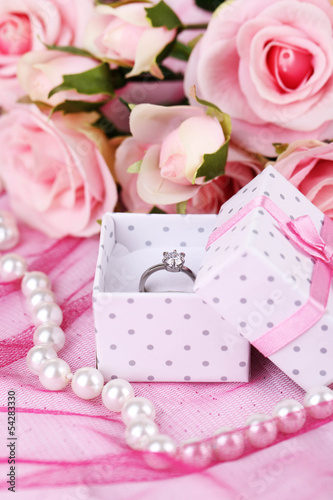 Rose and engagement ring on pink cloth