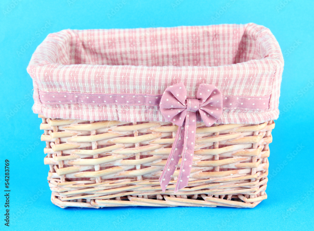 Wicket basket with pink fabric and bow, on color background Wicket basket with pink fabric and bow, on color background