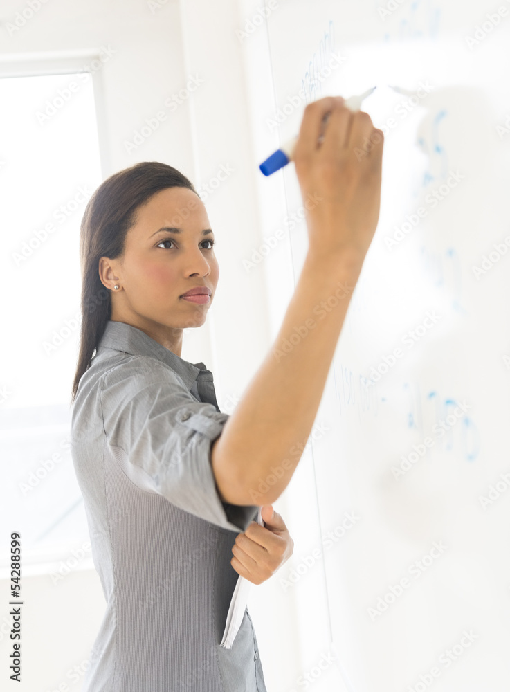 Beautiful Businesswoman Writing On Whiteboard In Office Beautiful Businesswoman Writing On Whiteboard In Office