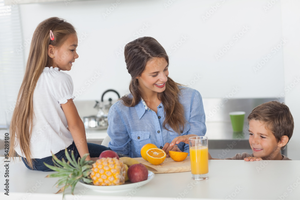 Attractive woman cutting an orange for her children Attractive woman cutting an orange for her children
