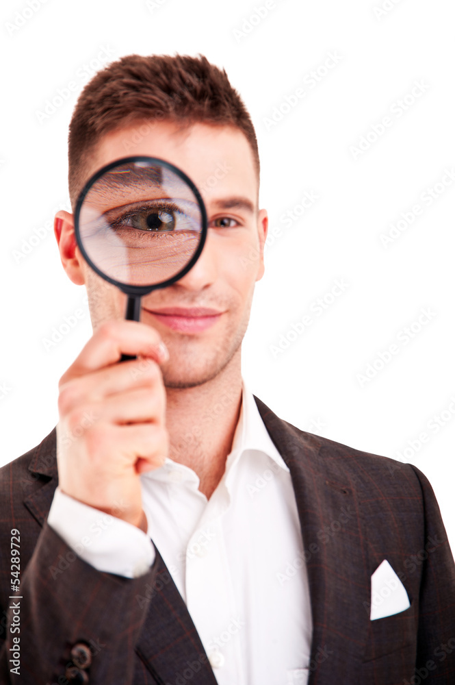 Young business man in suit looking to magnifying glass Young business man in suit looking to magnifying glass