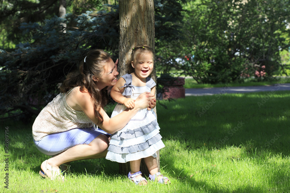 Fototapeta premium Joyful mother with a young daughter playing in a city park.