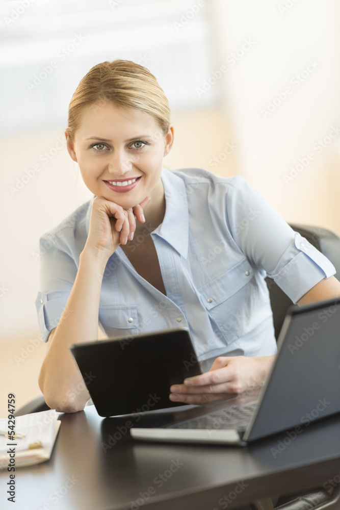 Businesswoman With Hand On Chin Holding Digital Tablet At Desk Businesswoman With Hand On Chin Holding Digital Tablet At Desk
