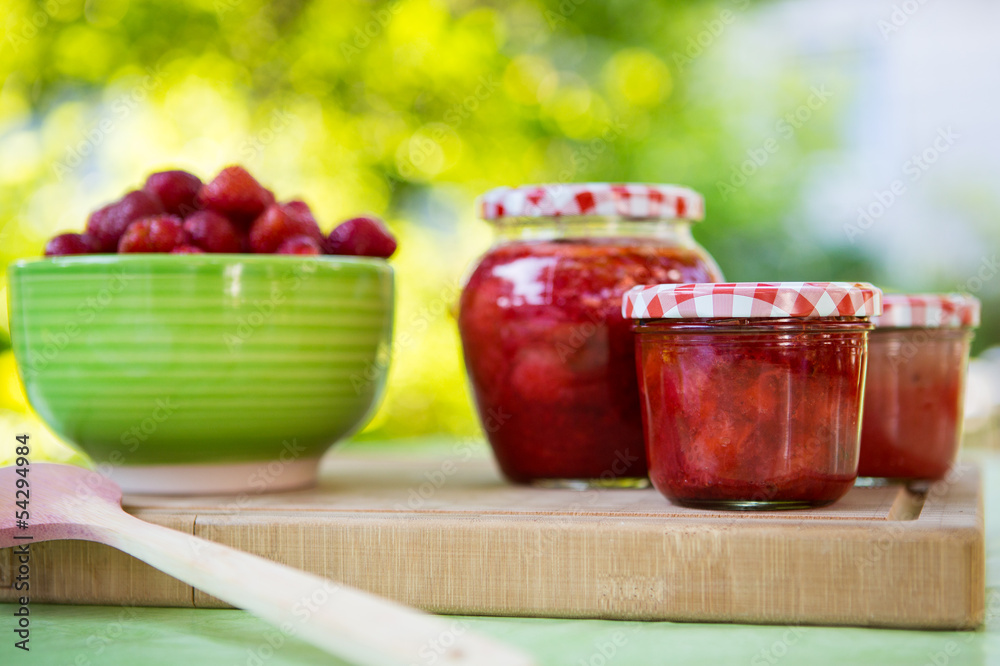 Homemade strawberry jam in different jars and fresh ripe strawbe Homemade strawberry jam in different jars and fresh ripe strawbe