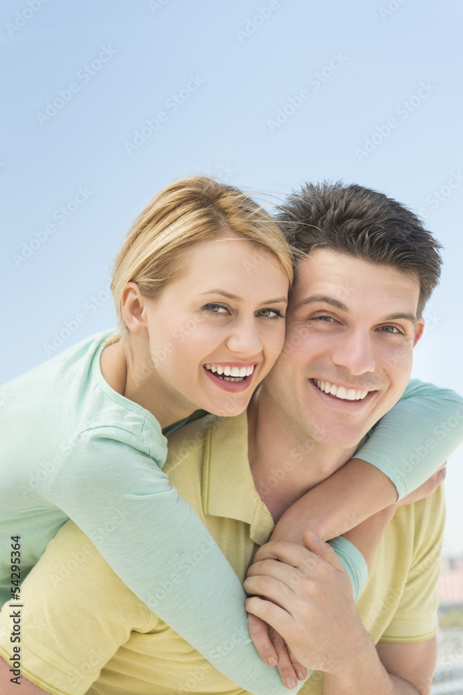 Playful Woman Embracing Man From Behind Against Clear Sky Playful Woman Embracing Man From Behind Against Clear Sky