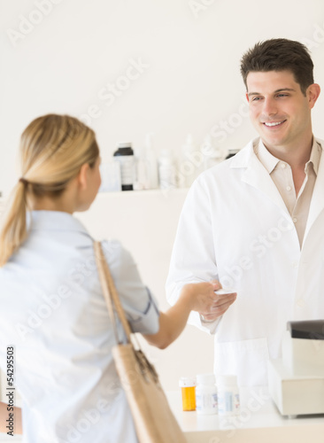 Customer Giving Prescription Paper To Pharmacist In Store