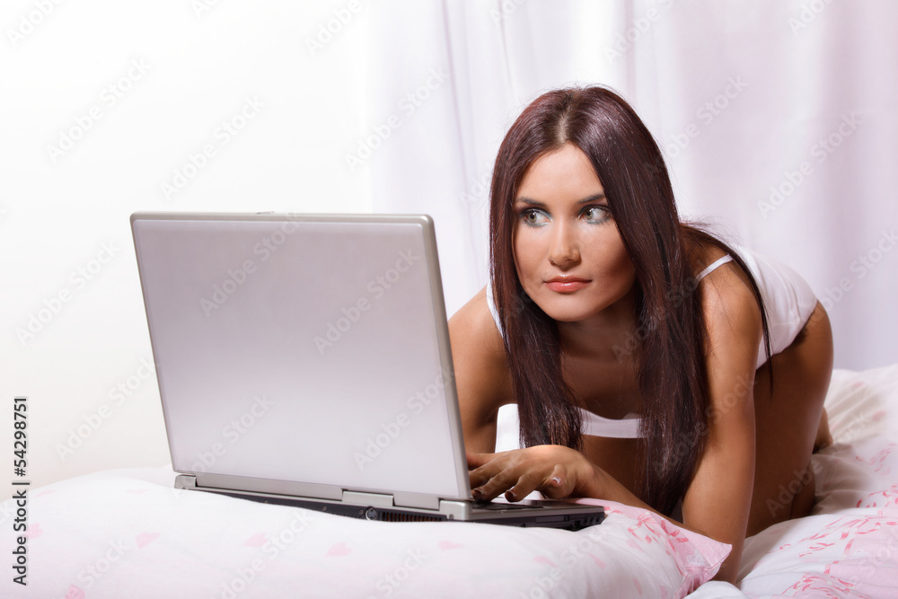 Young woman on bed using laptop Young woman on bed using laptop
