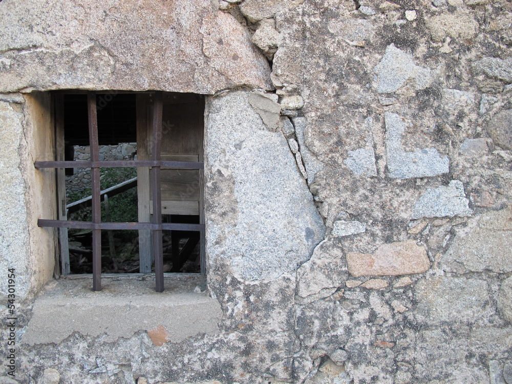 Fototapeta premium Old window with iron bars in stone wall