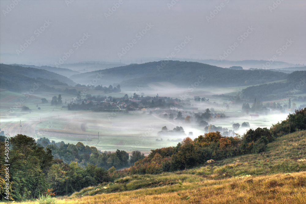 Obraz premium Rural mountain village in fog aerial view