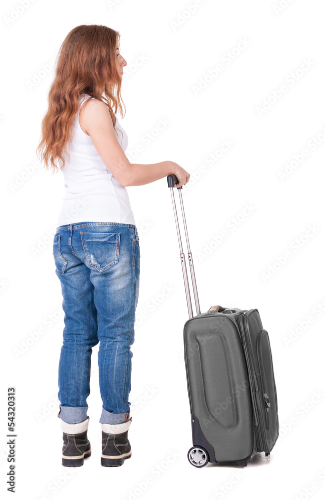 Back view of stylishly dressed woman with suitcase looking up