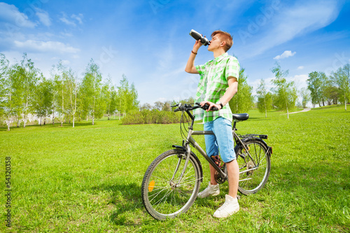 Young man on a bike drinking water