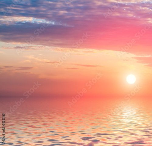 Dramatic sunset with clouds reflected in water.