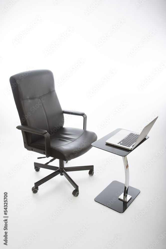 Black office chair and laptop on glass desk Black office chair and laptop on glass desk